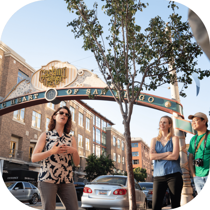 Tour guide speaking to guest in front of the San Diego Gaslamp Quarter sign