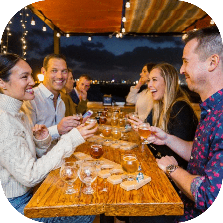 homepage-about-connection@2x A group of people laughing and drinking during San Diego food tour