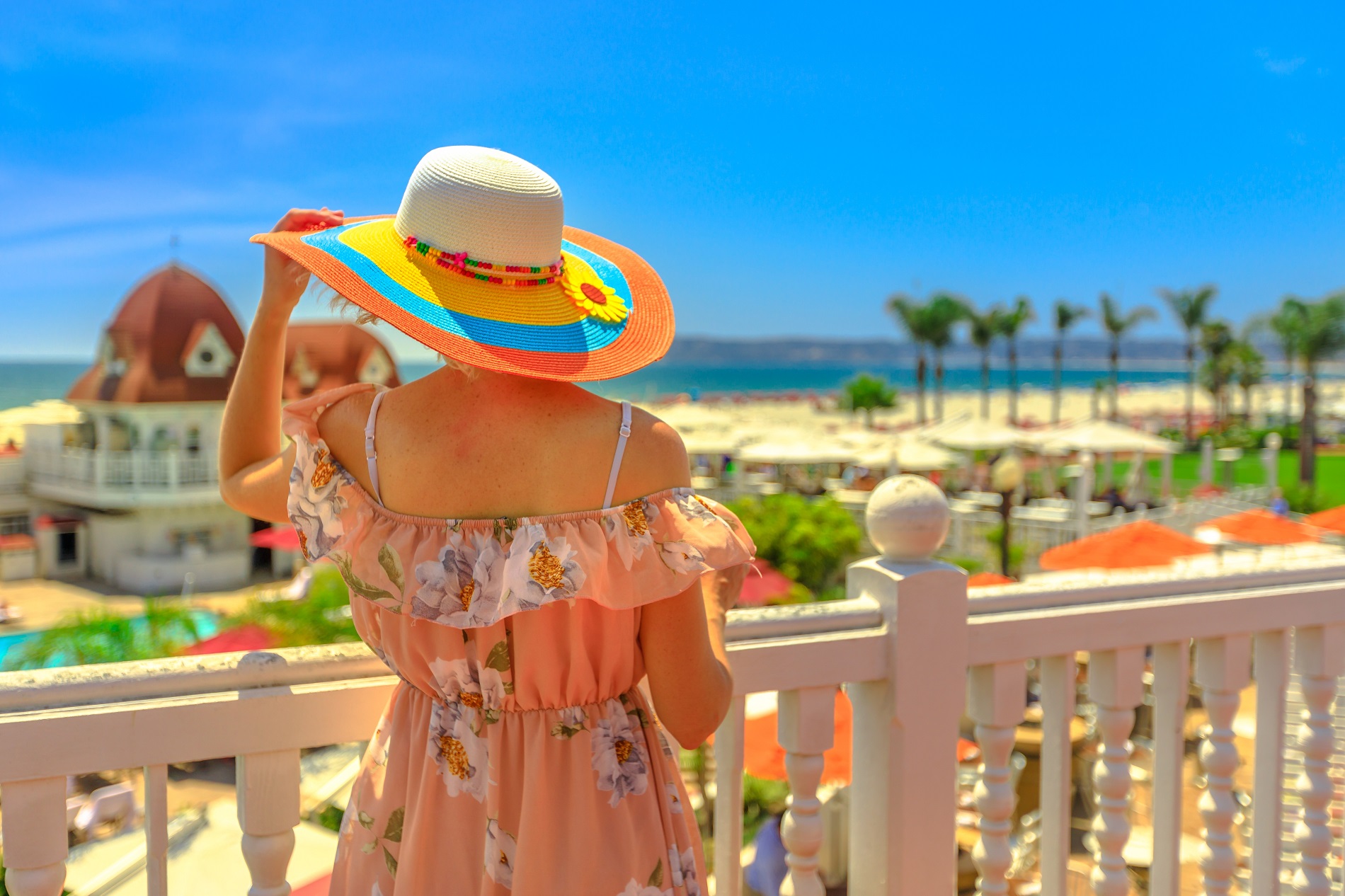 Tourist woman in hat at a balcony looking scenic arial view of West Coast in Pacific Ocean, Coronado Island, San Diego
