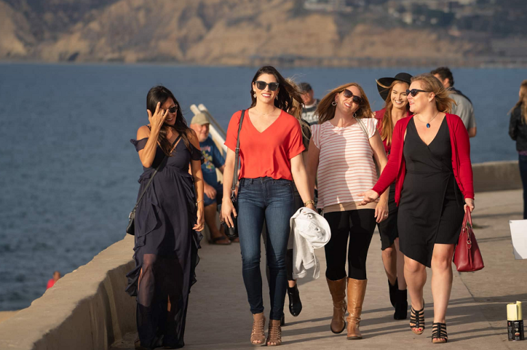 group of women walking with ocean in background