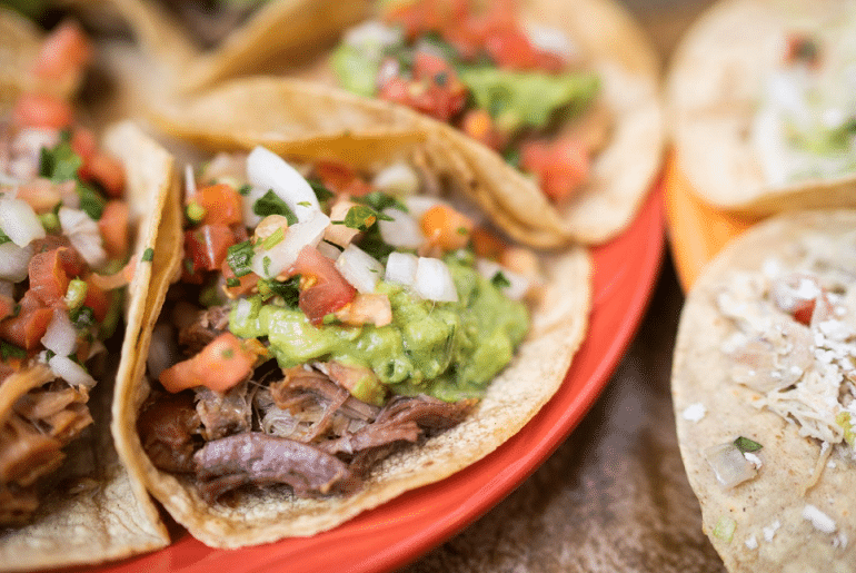 zoomed in plate of tacos with guacamole and pico de gallo