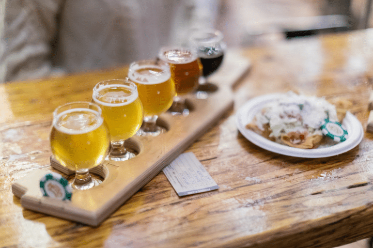 beer tasting flight sitting on a table next to a nacho plate