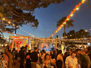 group of people watching band playing on stage at night with string lights across outdoor venue