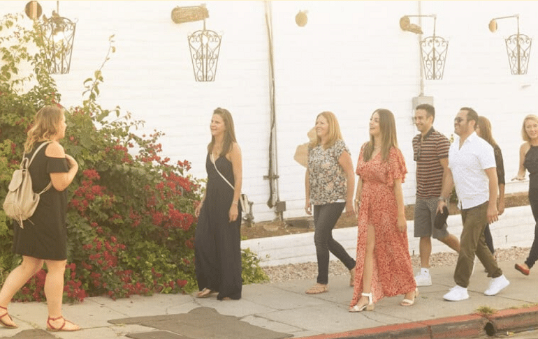 tour guide leading a group down a paved sidewalk