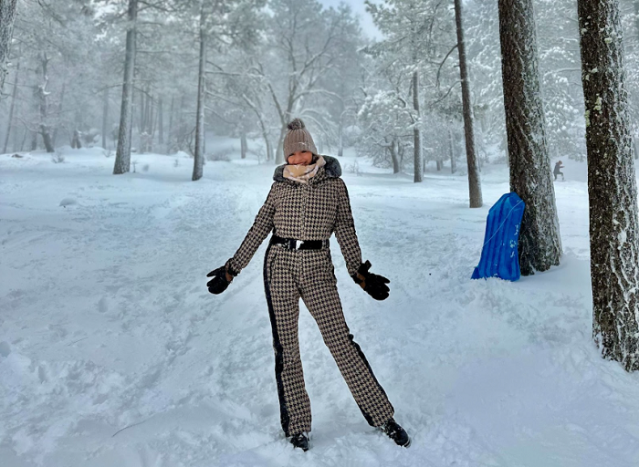 woman standing in snow posing next to trees