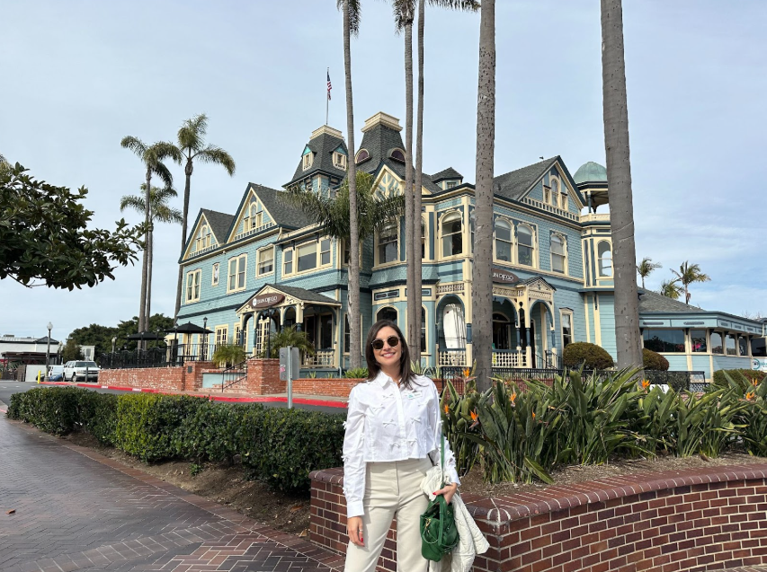 woman standing in front of blue historical building surrounded by palm trees