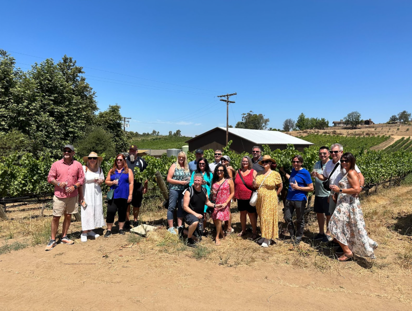 group of people standing in vineyard posing for a photo